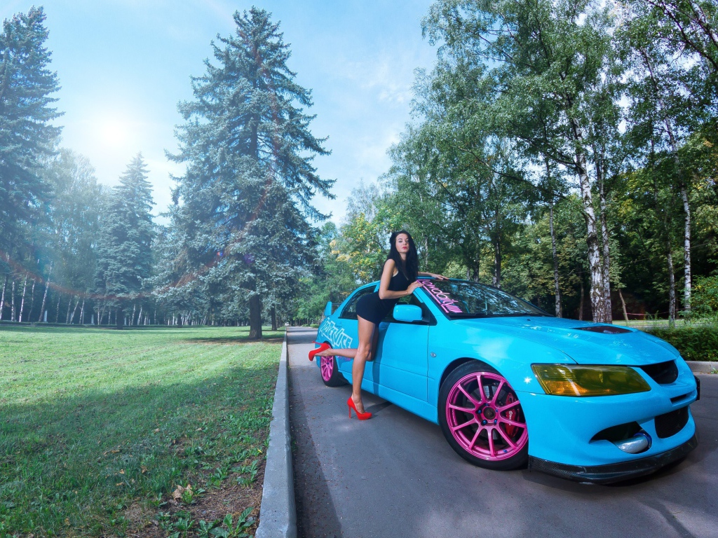Девушка облокотилась на голубой Mitsubishi Lancer Evo X