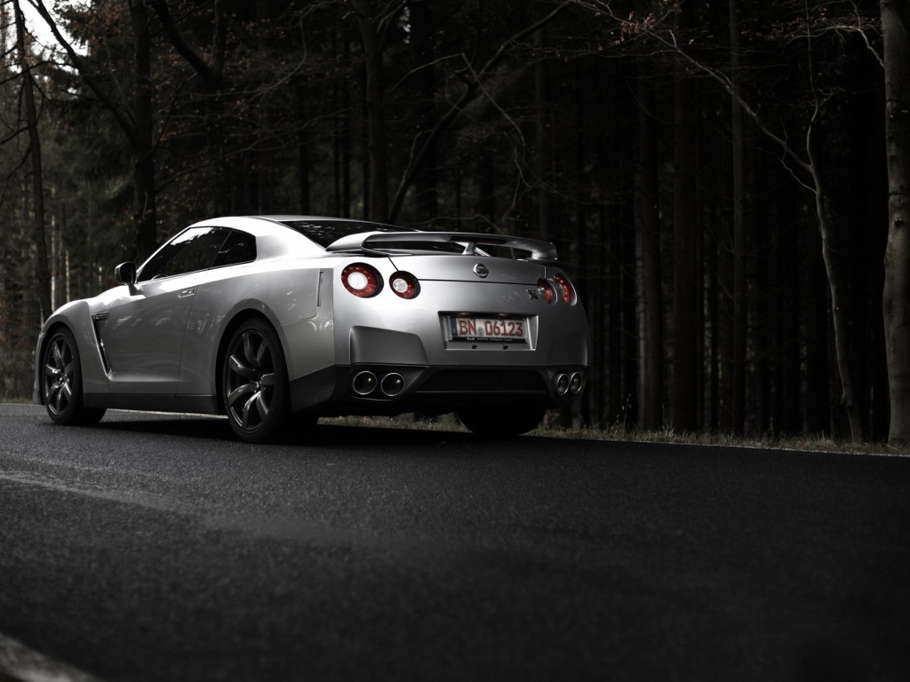 Серебристый Nissan GT-R на фоне темного леса