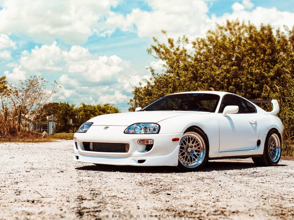 Белая Toyota Supra на фоне зелени