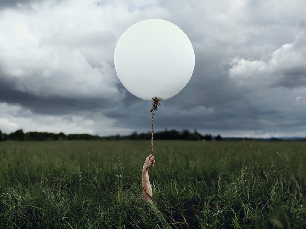 Рука с шаром среди поля