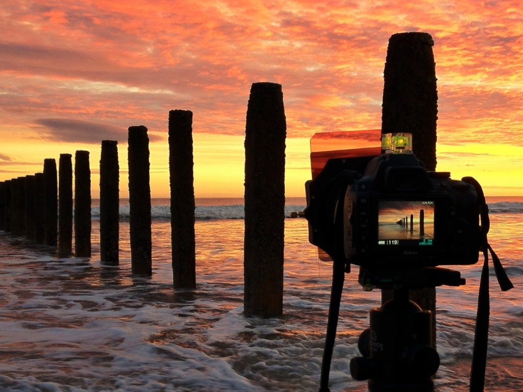 Фотограф снимает закат на берегу моря