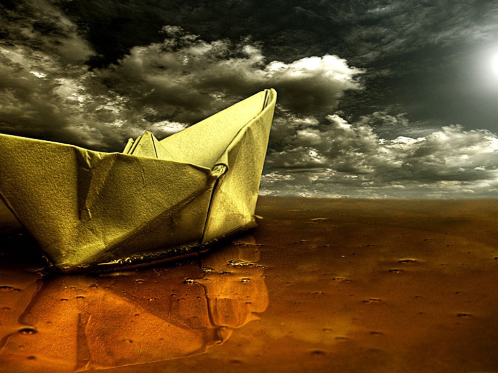 Корабль из бумаги на мокром песке