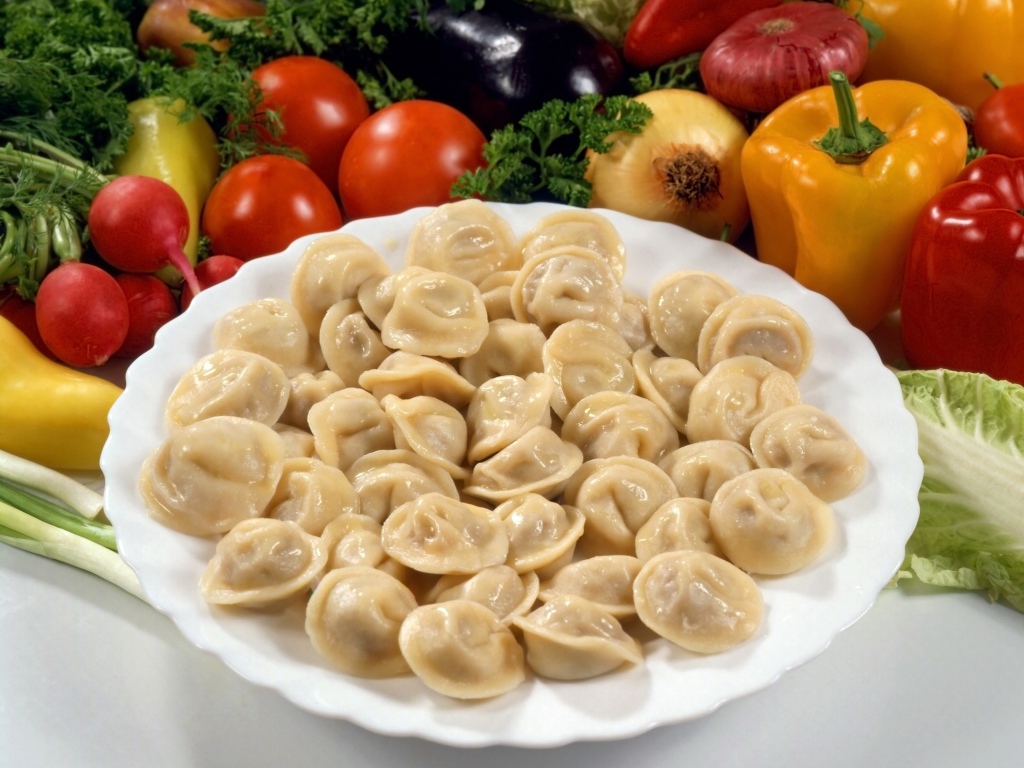 Пельмени на тарелке среди овощей