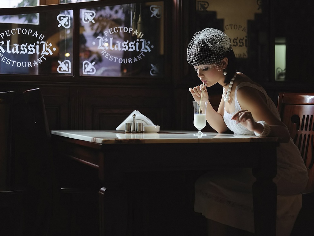 Девушка в белом платье пьет коктейль в ресторане
