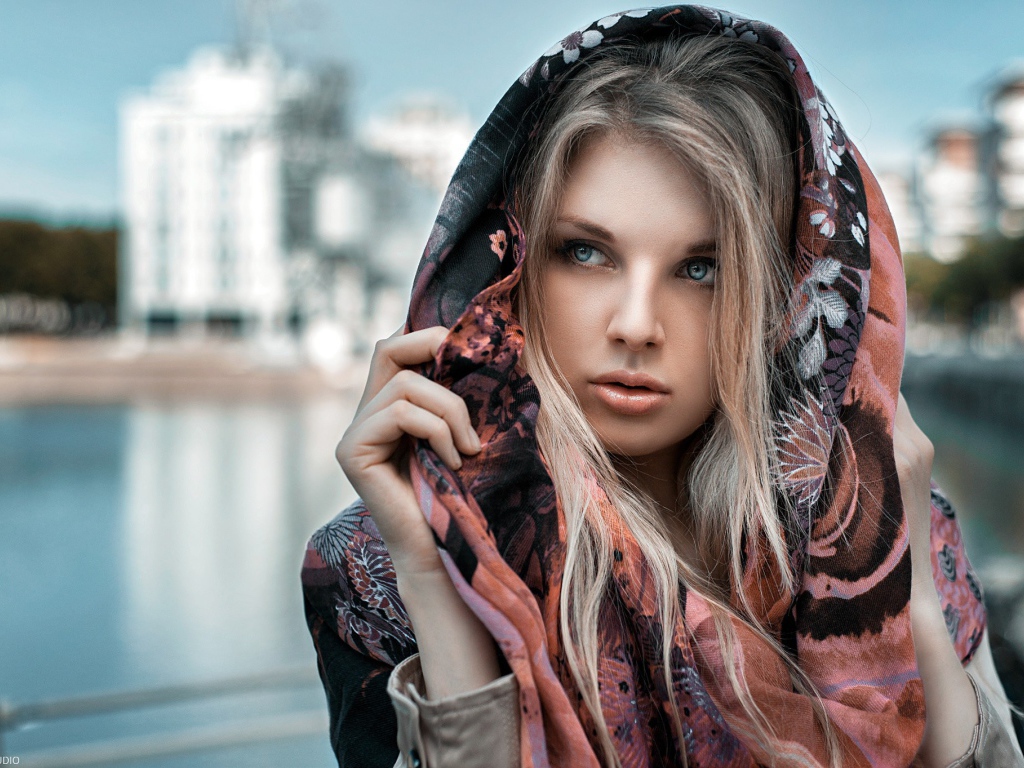 Блондинка в накидке на фоне городского пруда