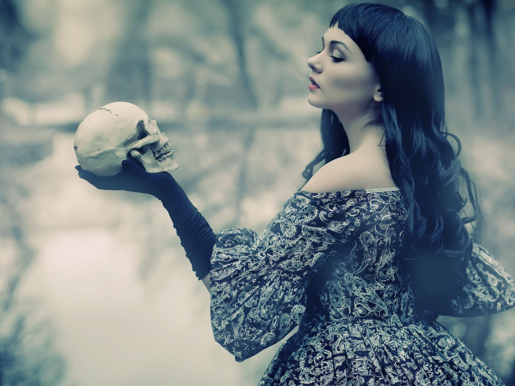Брюнетка держит в руке череп