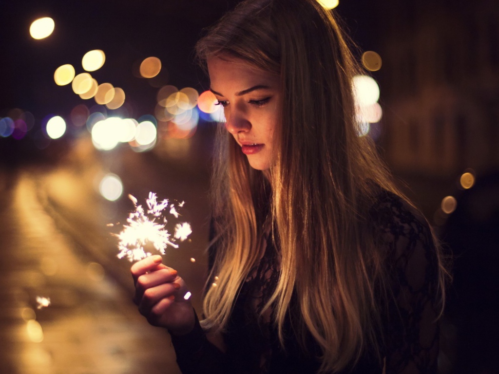 Девушка держит в руке бенгальский огонь