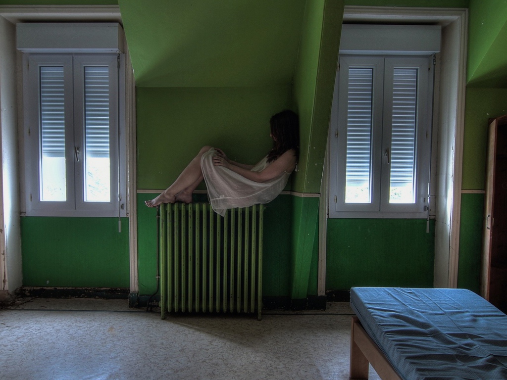 Девушка в ночной рубашке сидит на батарее