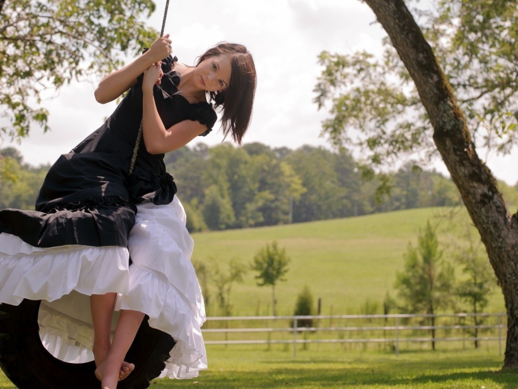 Девушка в черном платье на качелях