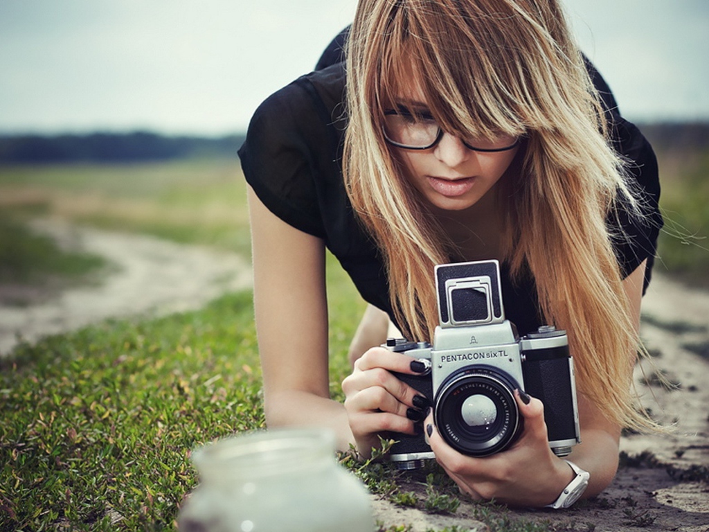 Девушка в очках фотографирует траву