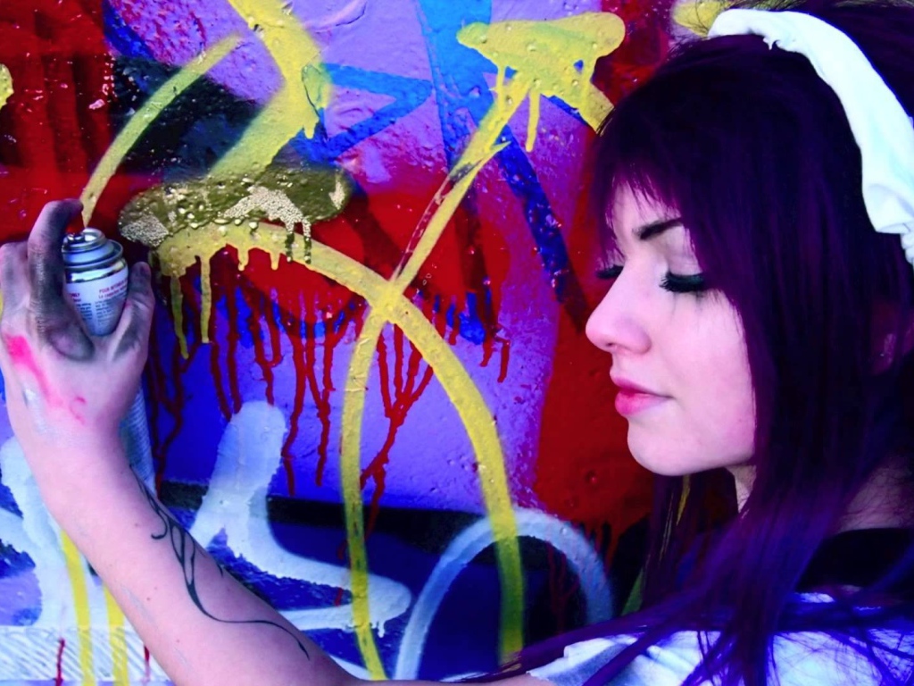 Девушка рисует граффити на стене