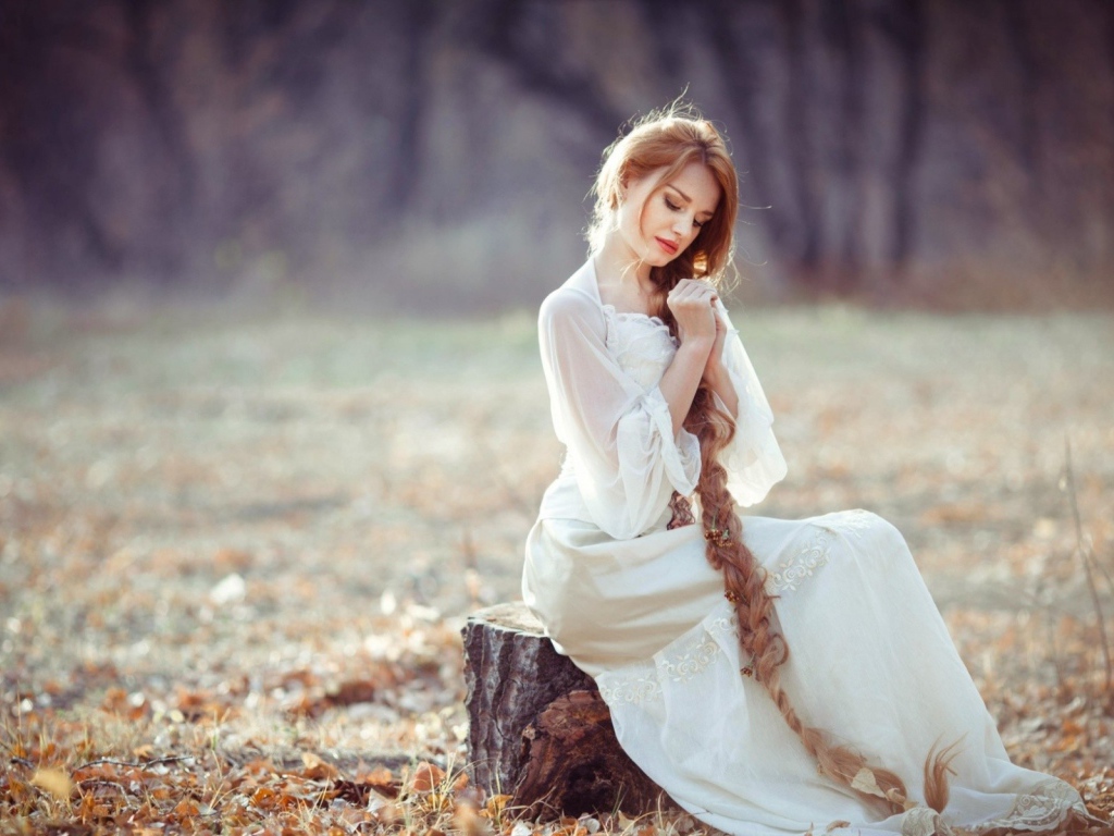 Девушка с косой сидит на пеньке