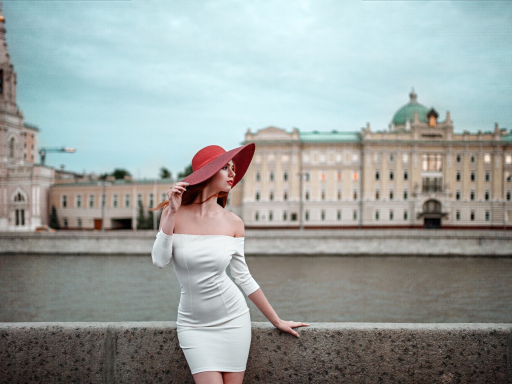 Девушка в белом платье и красной шляпе на набережной