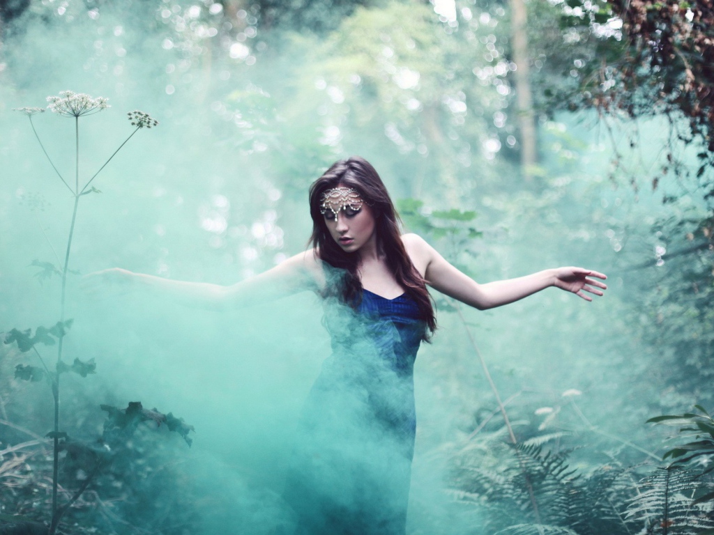 Девушка идет среди дыма по лесу