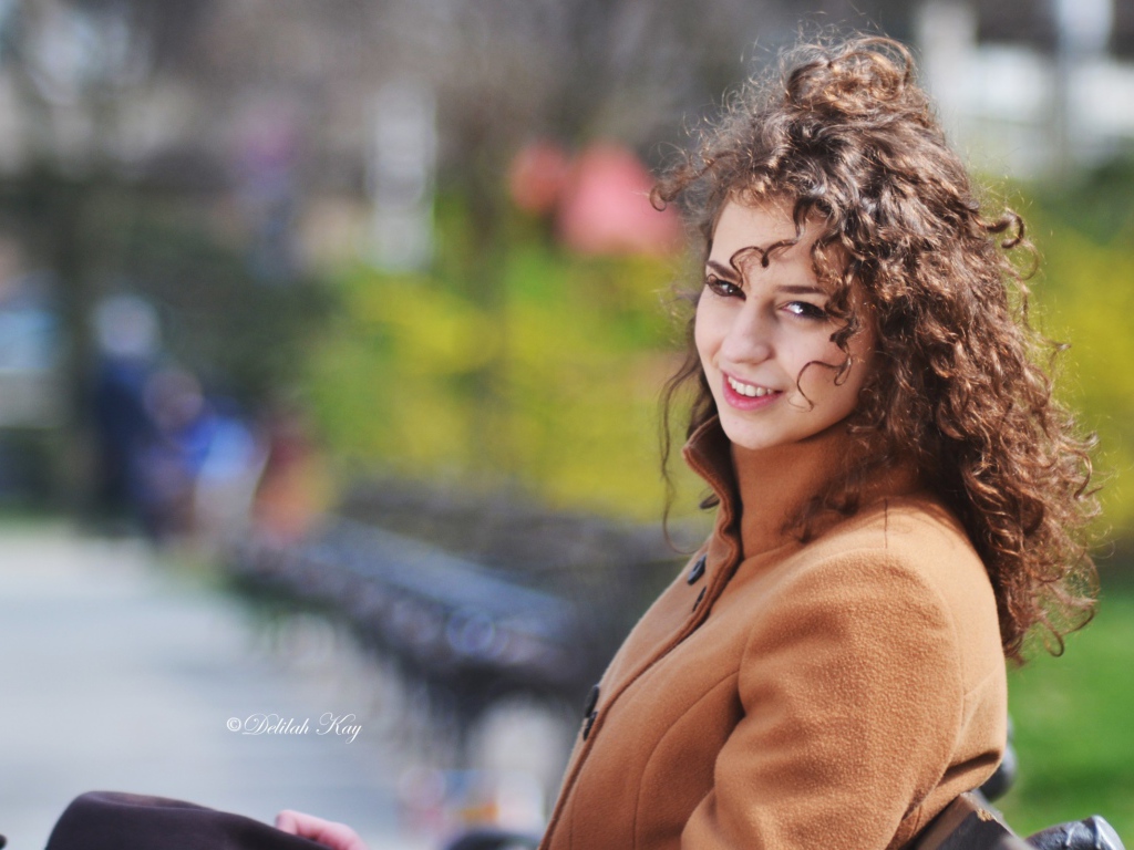 Ветер треплет волосы кучерявой девушки