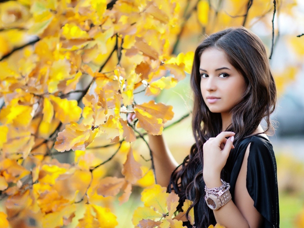 Молодая брюнетка у осеннего дерева