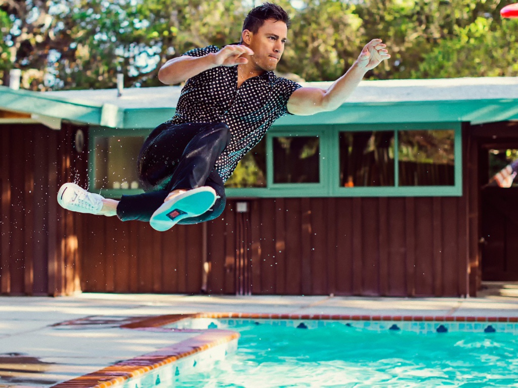 Мужчина прыгает в бассейн в одежде