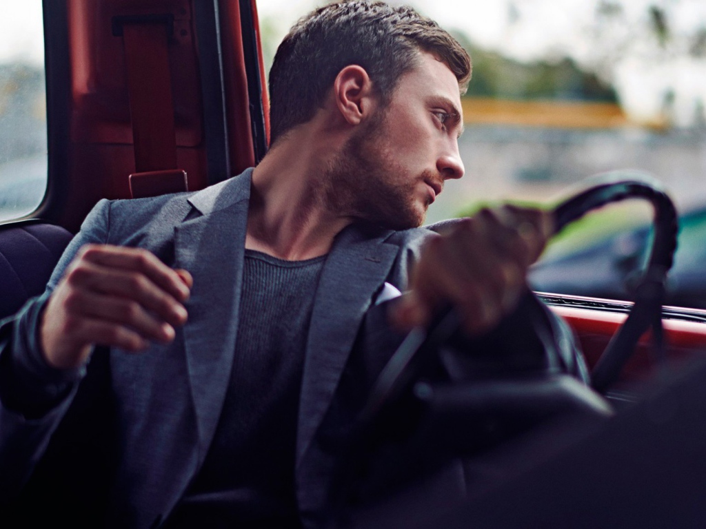 Мужчина за рулем смотрит в окно автомобиля