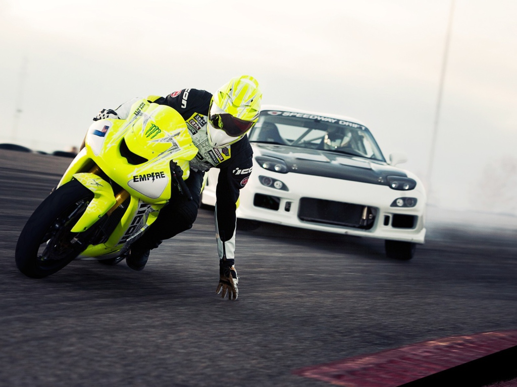 Мотоциклист касается рукой поверхности трека