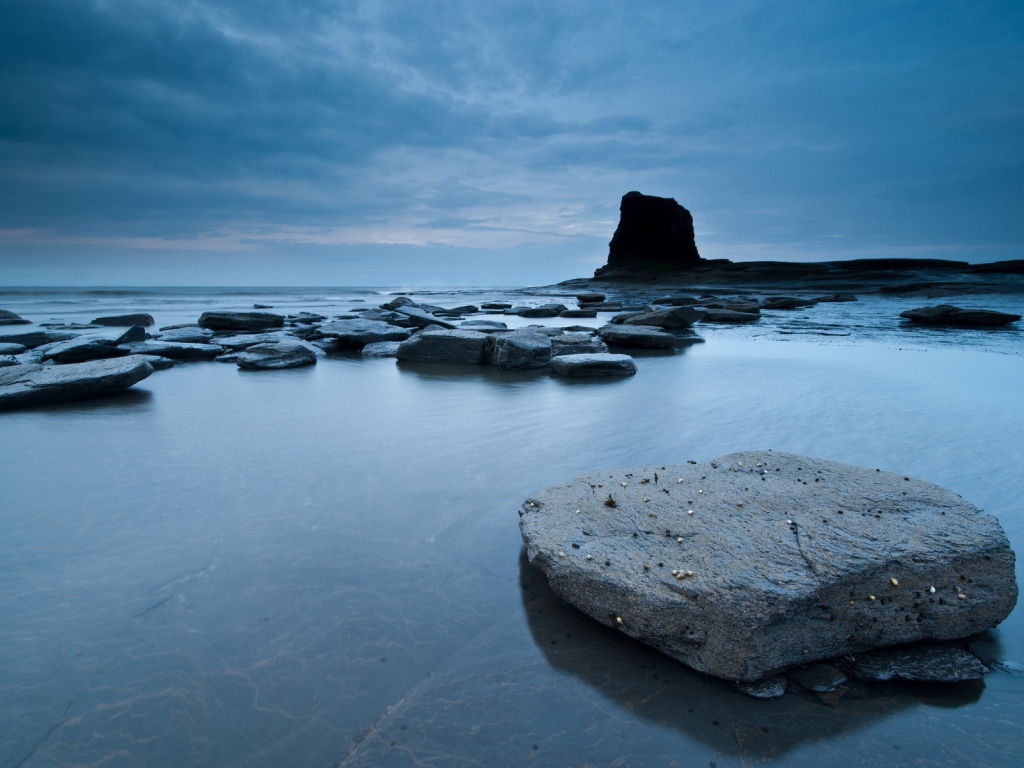 Плоские камни в серой воде у берега