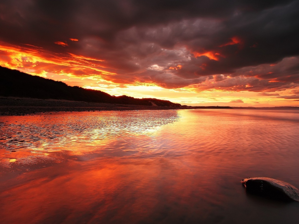 Камень на мелководье на фоне красного заката