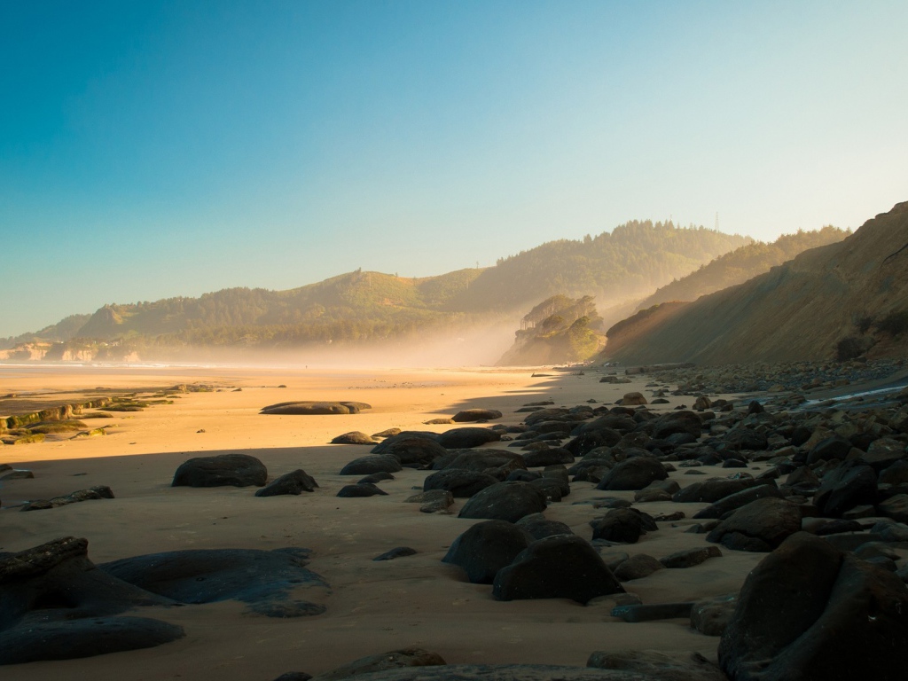 Черные круглые камни на песке пляжа