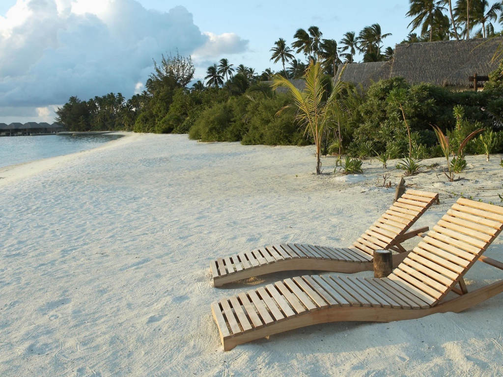 Деревянные шезлонги на белом песке пляжа
