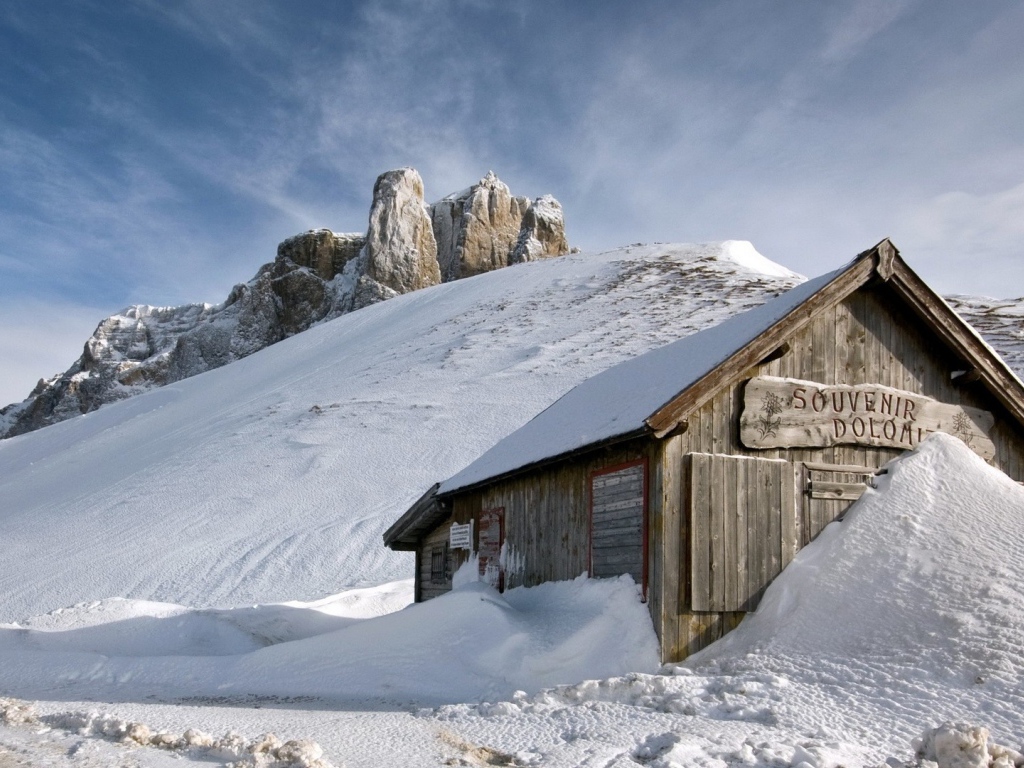 Деревянный домик замело снегом в горах