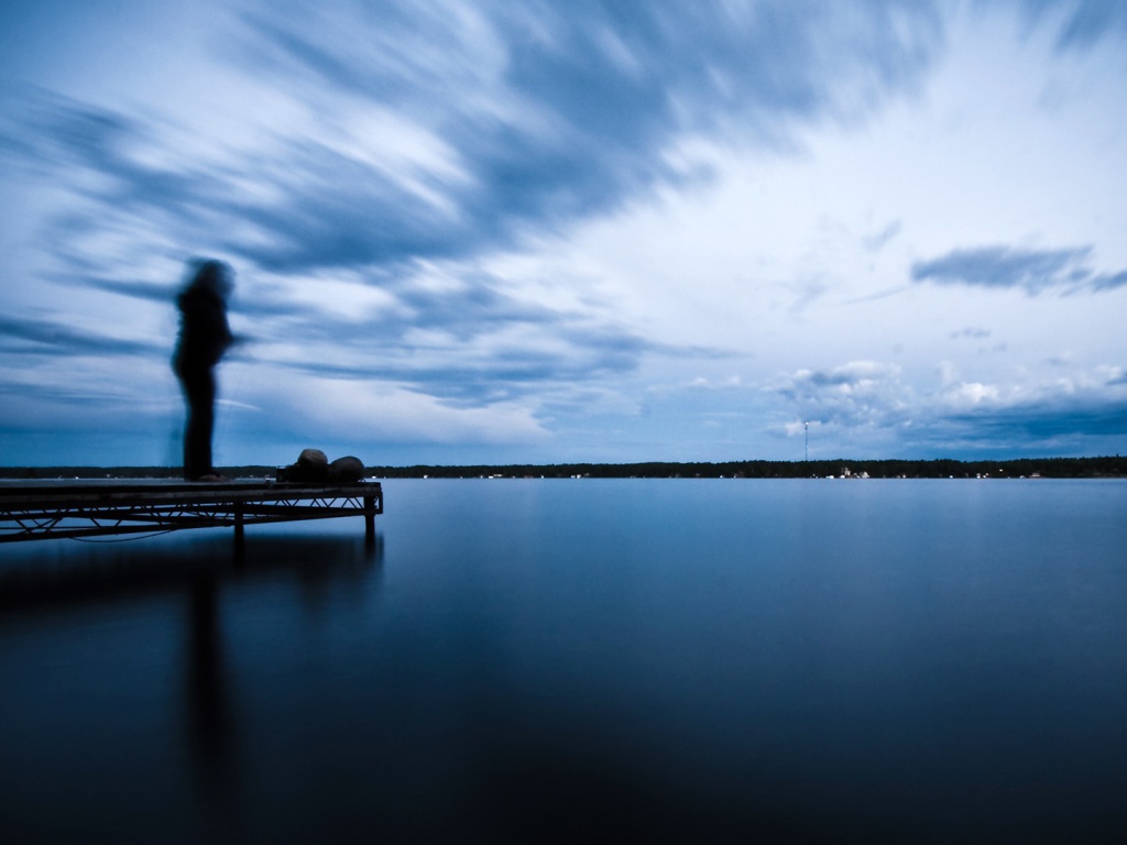 Силуэт человека на пристани у озера