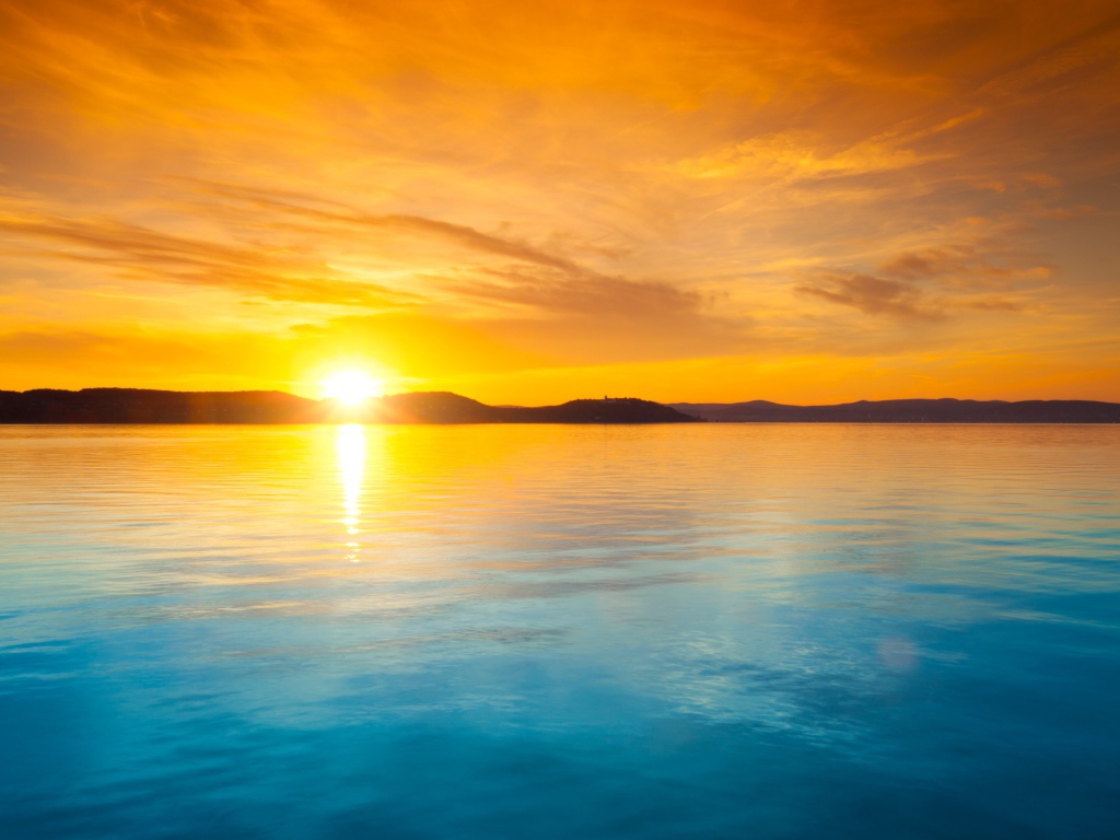 Оранжевое небо над голубой водой на закате