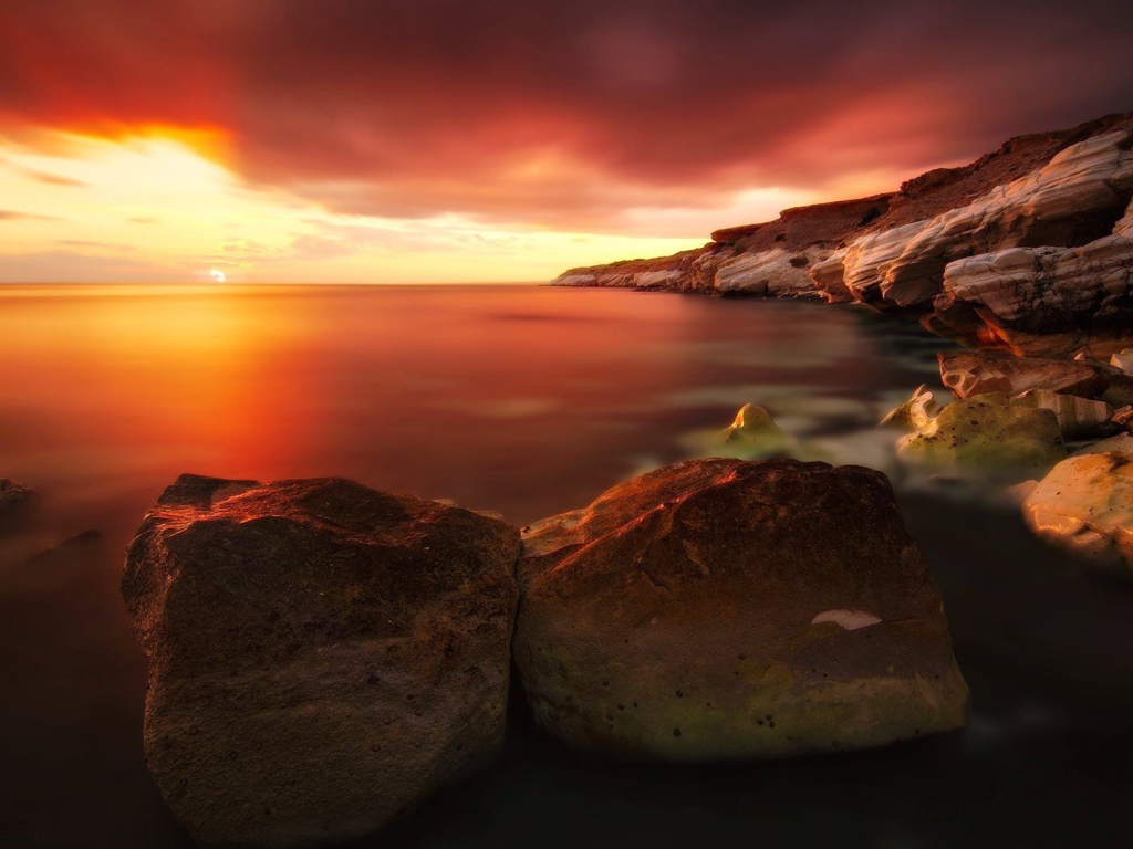 Два больших камня на берегу моря на закате