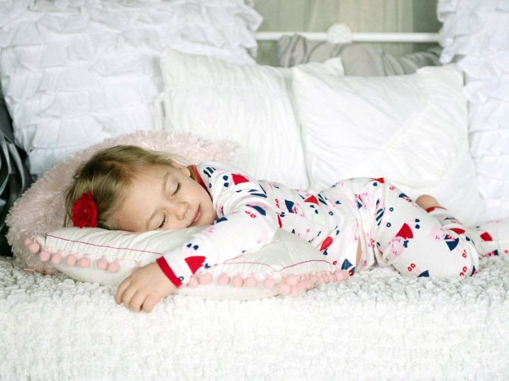 Девочка в пижаме спит на кровати