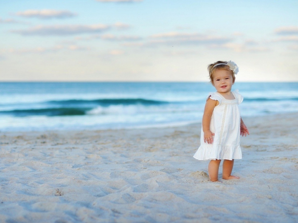 Девочка в белом платье на песке пляжа