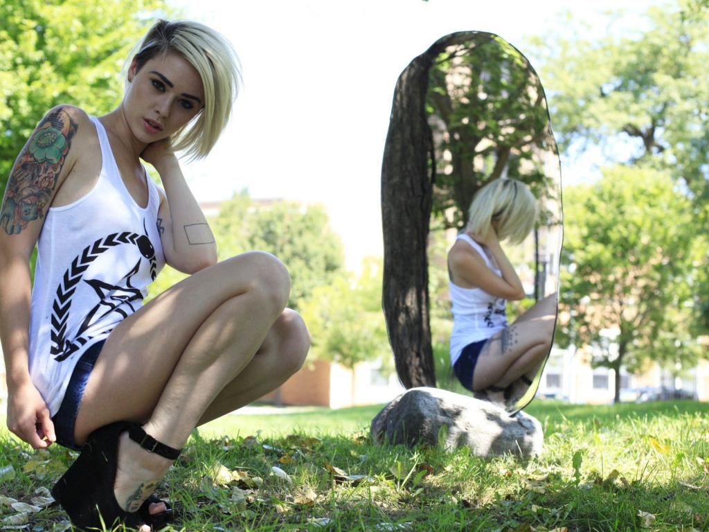 Девушка с тату на природе у зеркала