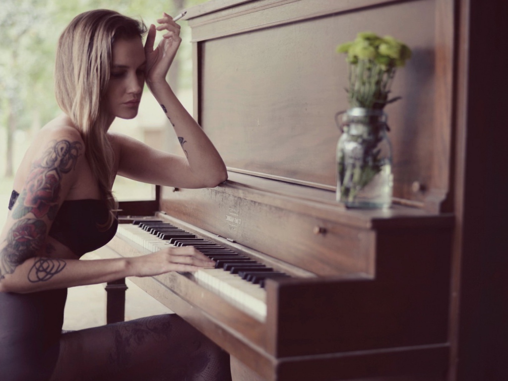 Девушка с тату играет на пианино