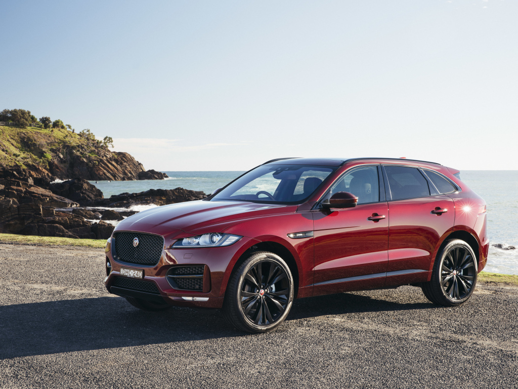 Бордовый автомобиль Jaguar F-Pace на фоне океана