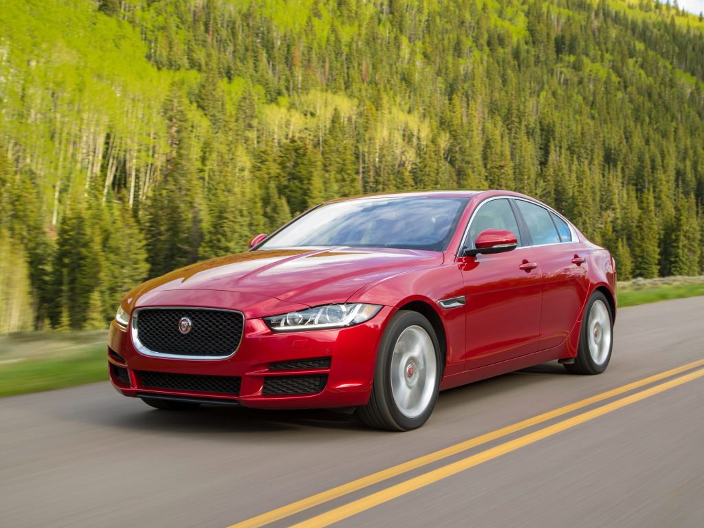 Автомобиль красного цвета Jaguar XE на трассе 