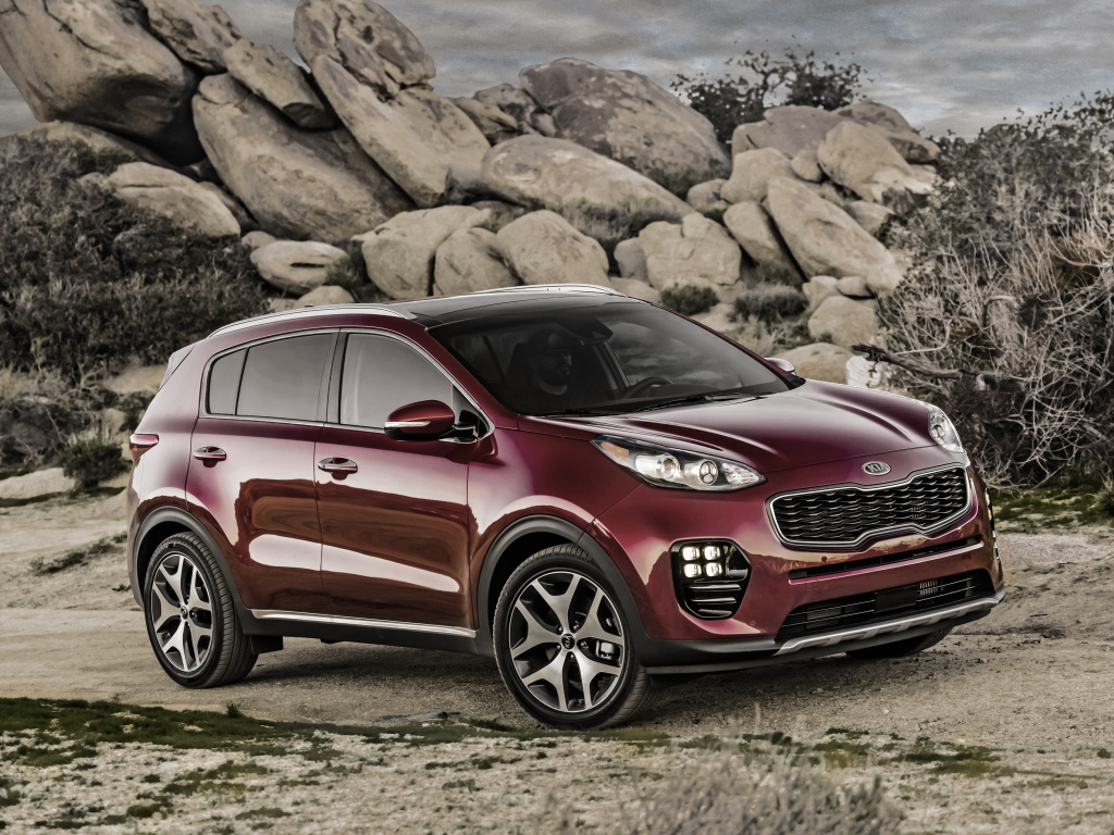 Стильный бордовый внедорожник Kia Sportage на фоне больших камней