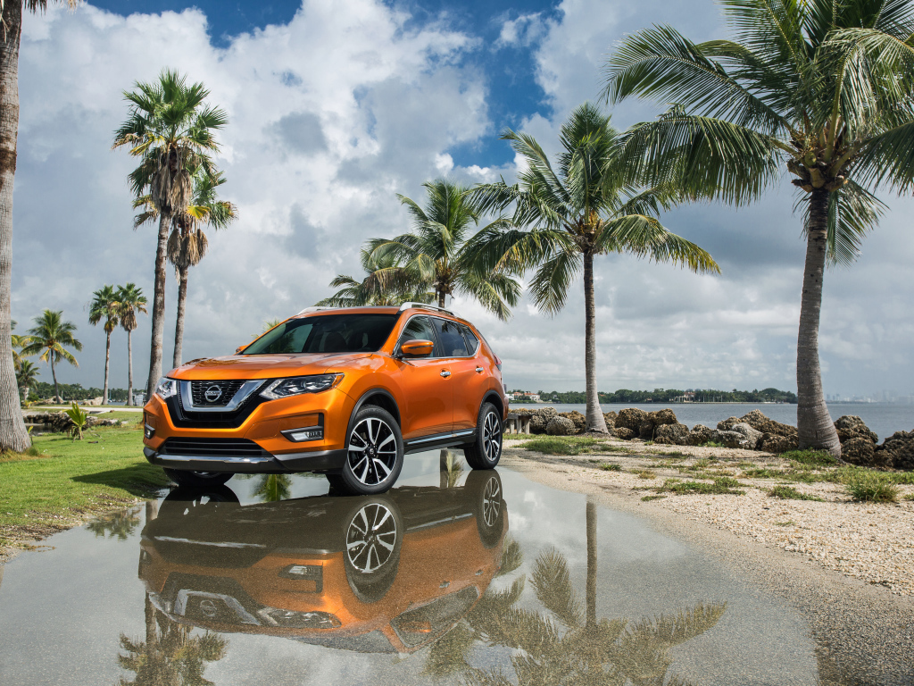 Оранжевый внедорожник Nissan Rogue на фоне пальм