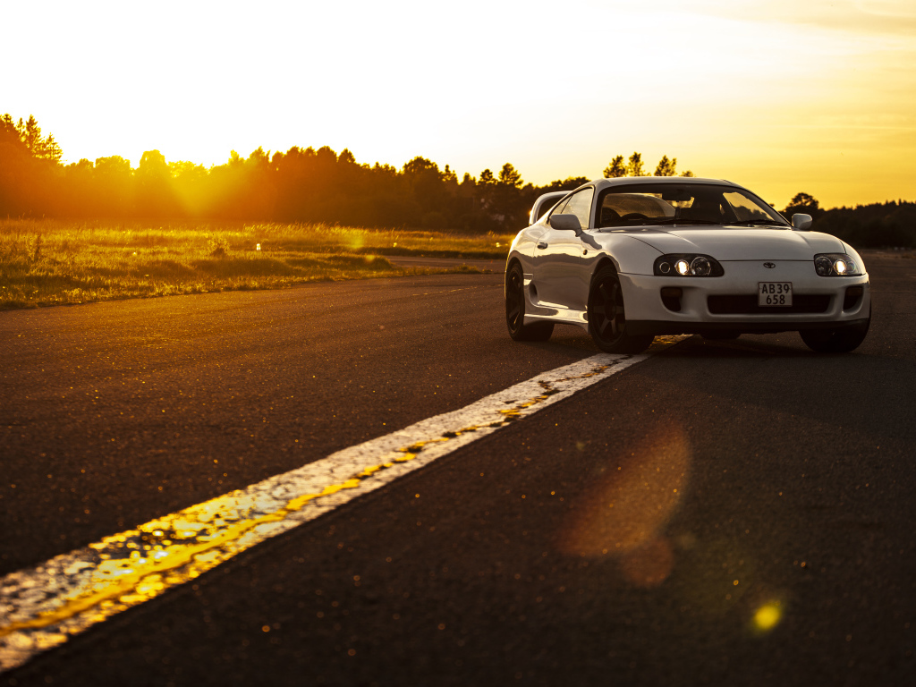 Белый автомобиль Toyota Supra стоит на трассе на рассвете