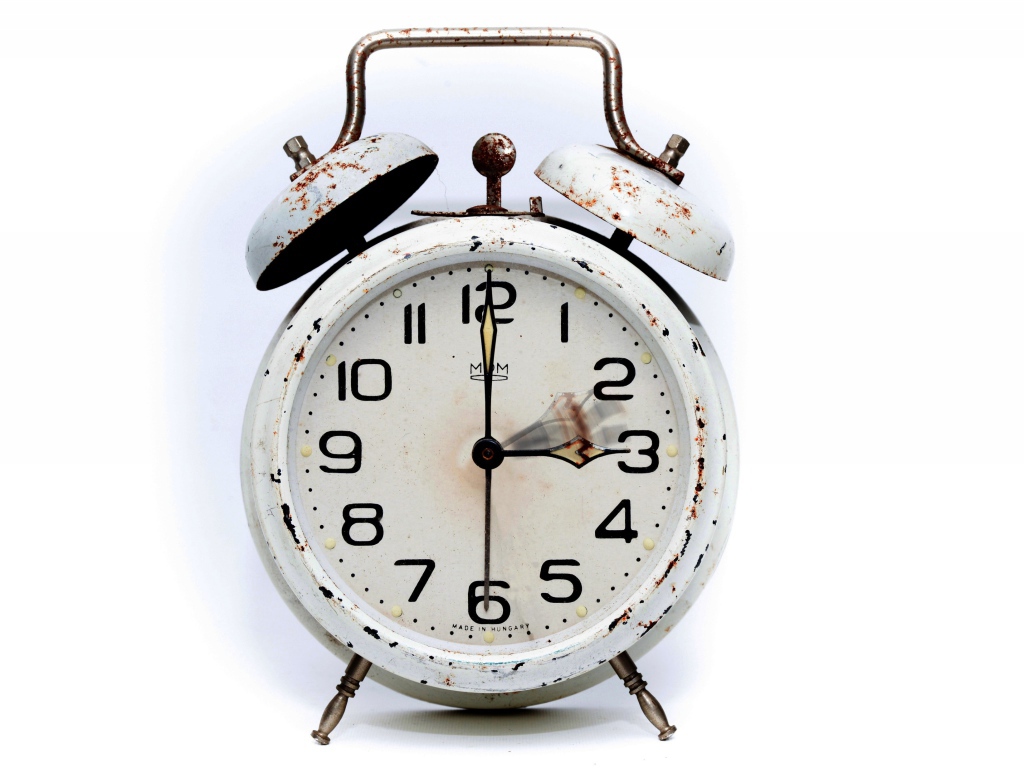 Старый будильник с большим циферблатом на белом фоне