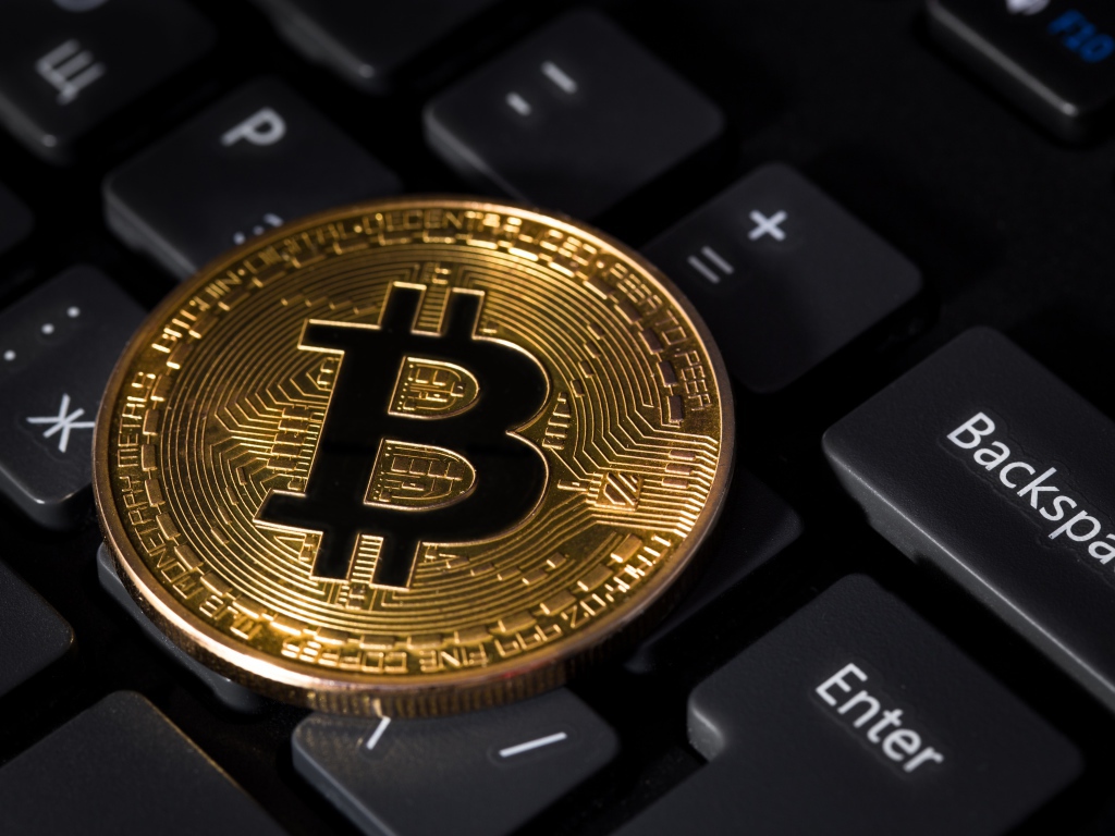 Монета биткоин лежит на черной клавиатуре