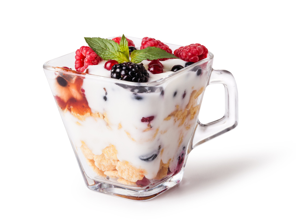Хлопья с йогуртом и ягодами в стакане на белом фоне