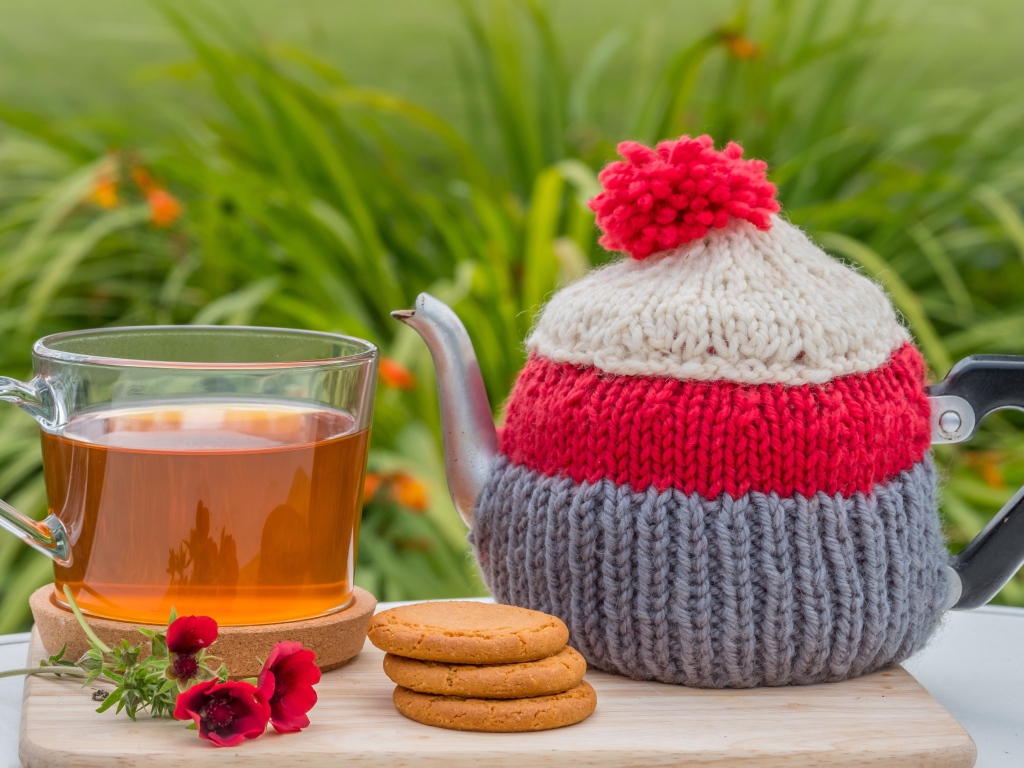 Чайник с чашкой чая на столе с печеньем и цветами