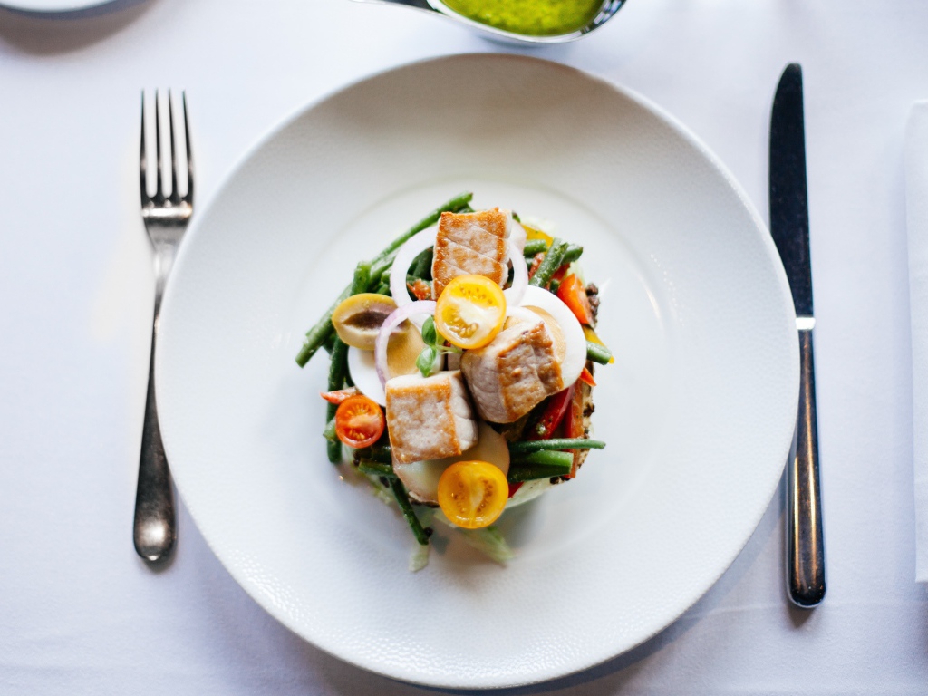 Овощной салат на белой тарелке со столовыми приборами