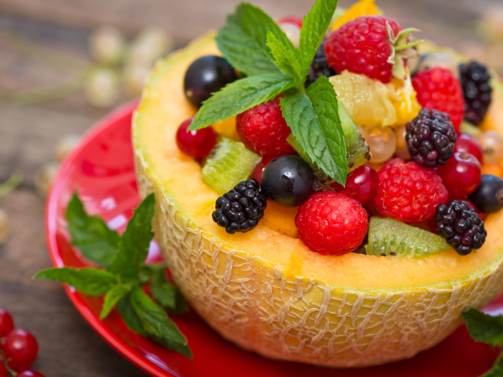 Аппетитные свежие ягоды с листьями мяты в половине дыни