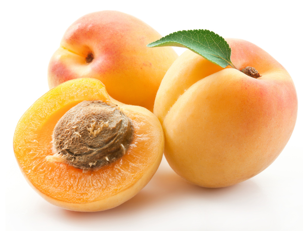 Три спелые крупные абрикосы на белом фоне