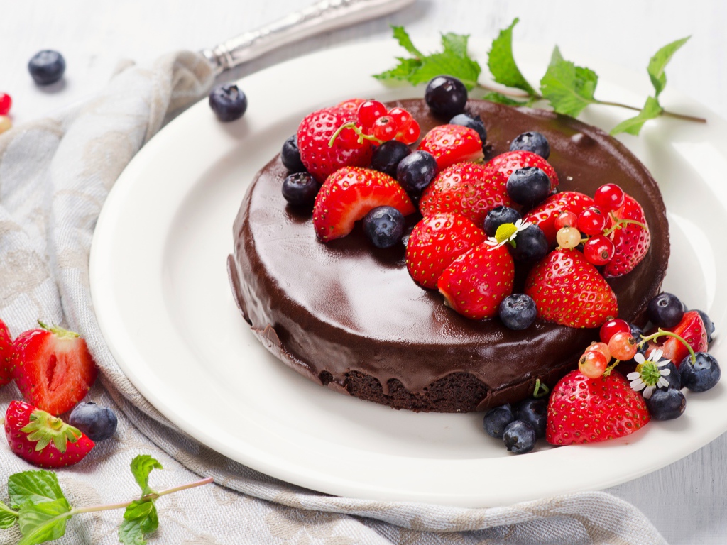 Вкусный торт в шоколаде с ягодами свежей клубники и черники