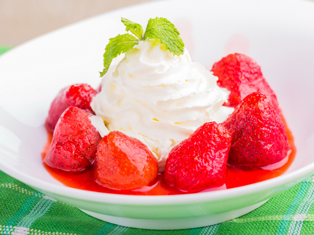 Вкусные сливки с клубникой на белой тарелке