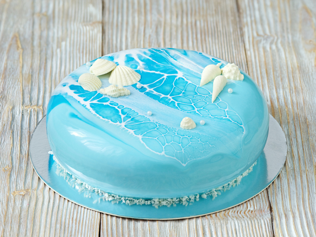 Глянцевый торт голубого цвета украшен сахарными ракушками